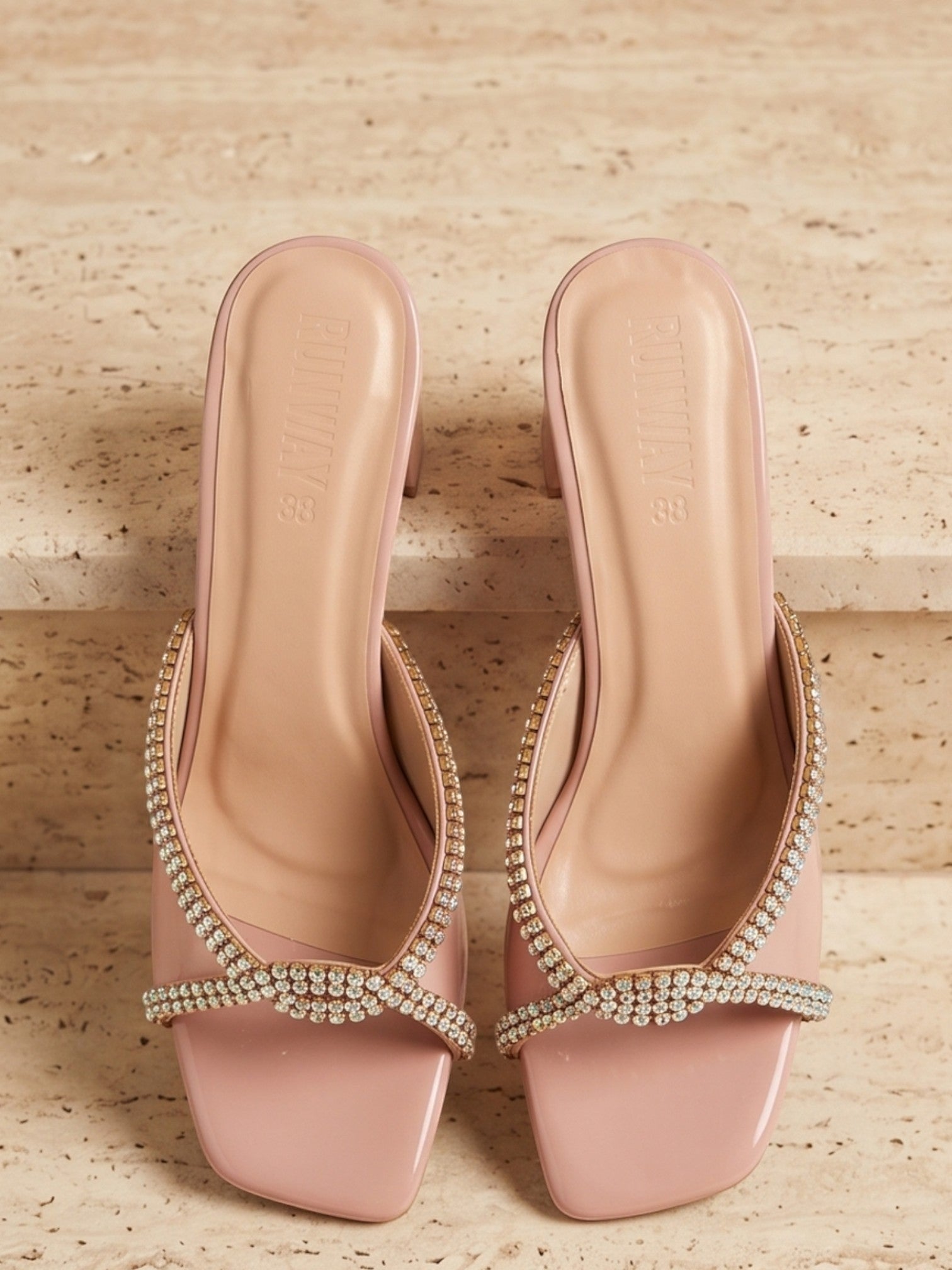 Runway Stores blush pink block heel slide sandals with crystal embellished crisscross straps and square toe design.